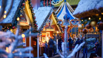 Festlig julmarknadsscen med snödammade stånd, dekorerade med ljus och girlanger. Folk samlas runt ett kaffeställ och njuter av den glada atmosfären. En färgglad karusell är synlig i bakgrunden, vilket bidrar till semesterkänslan.